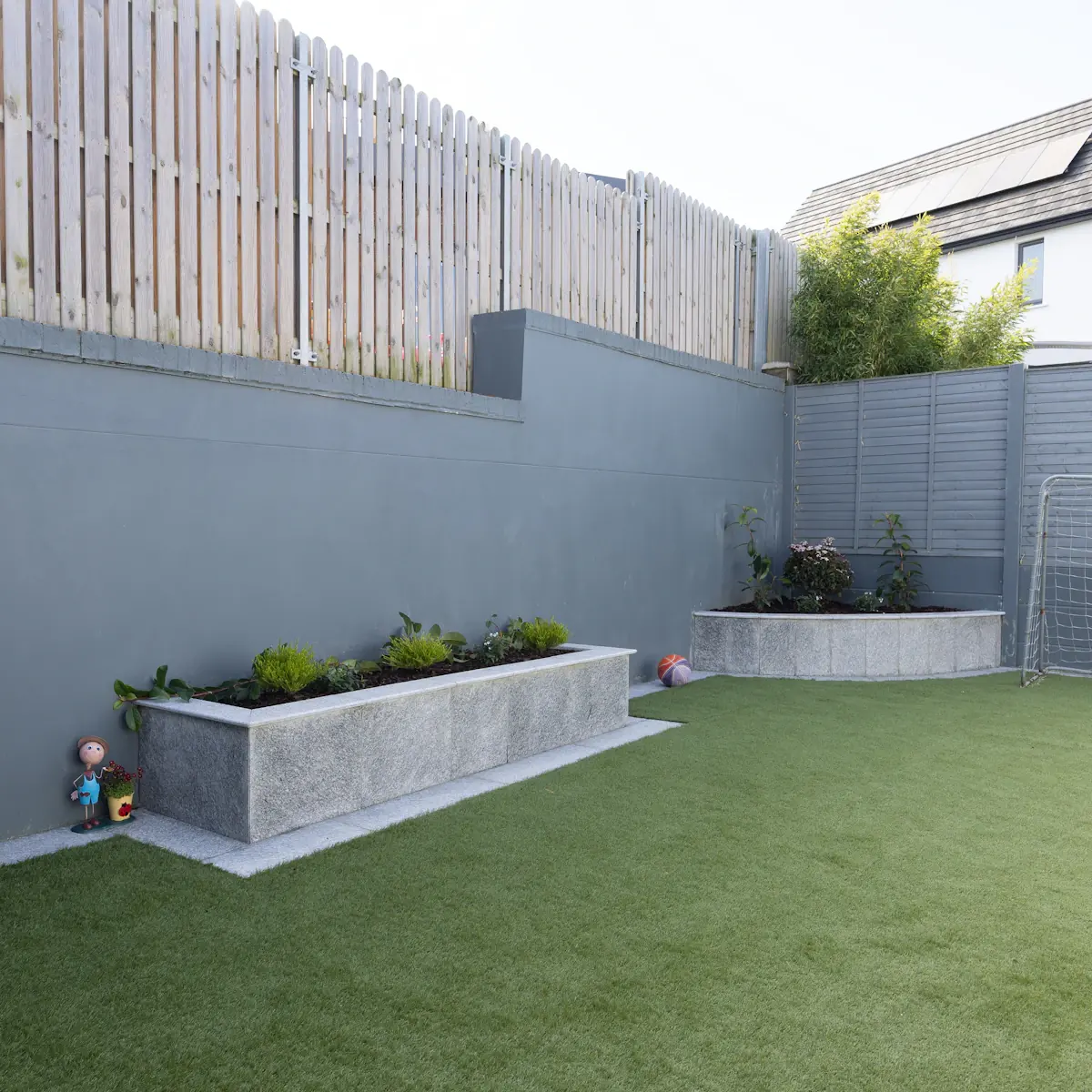Artificial grass installed in a residential backyard with concrete raised planters